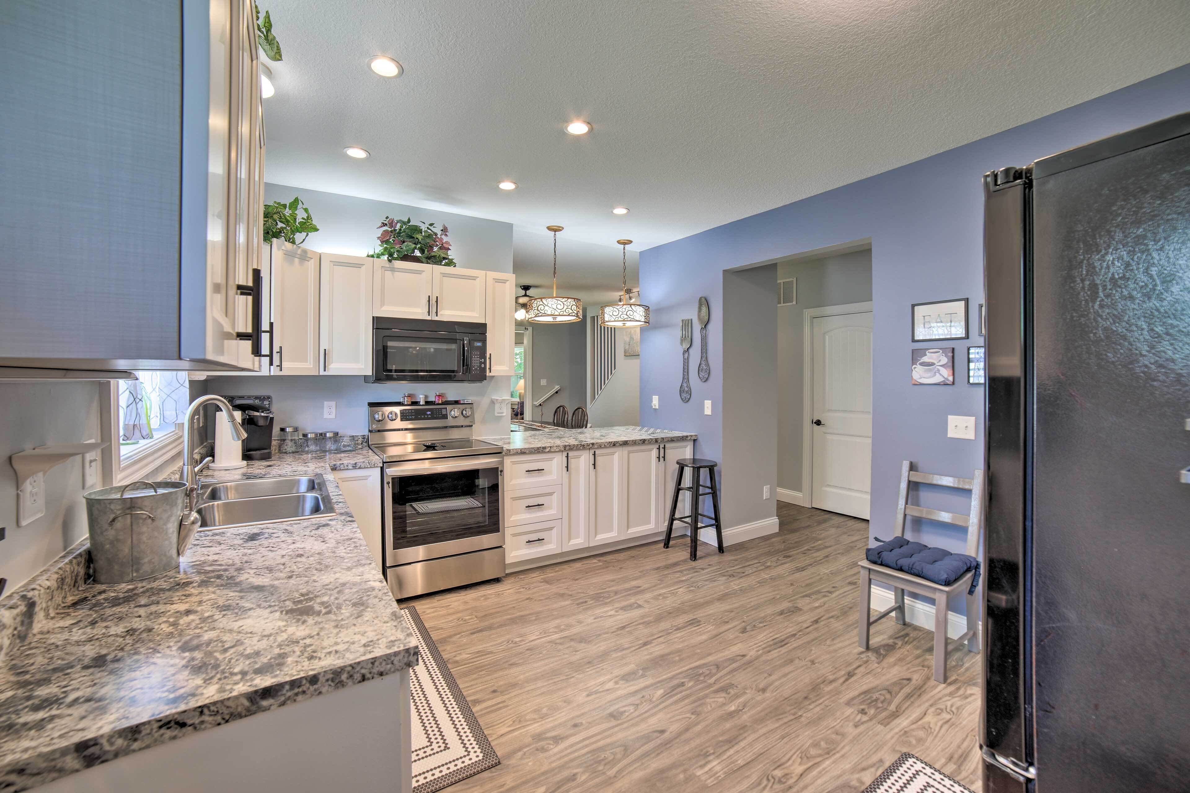 A modern kitchen with white cabinets, stainless steel appliances, and a marble countertop.