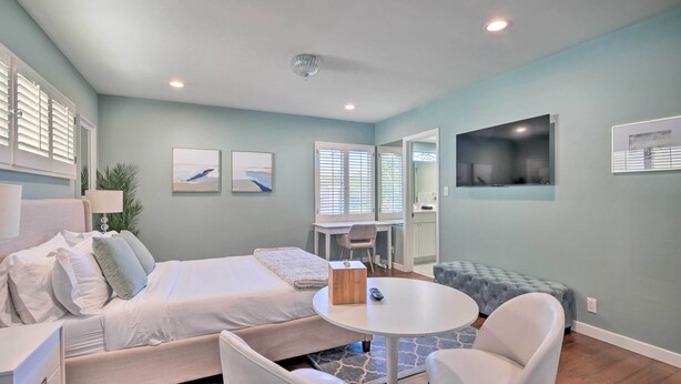A modern bedroom with a bed, a desk, a chair, and a small table.