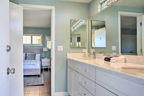 A modern bathroom with a large mirror, two sinks, and a vanity.