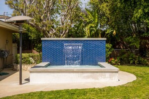 A rectangular pool with a blue tiled wall and a waterfall feature.