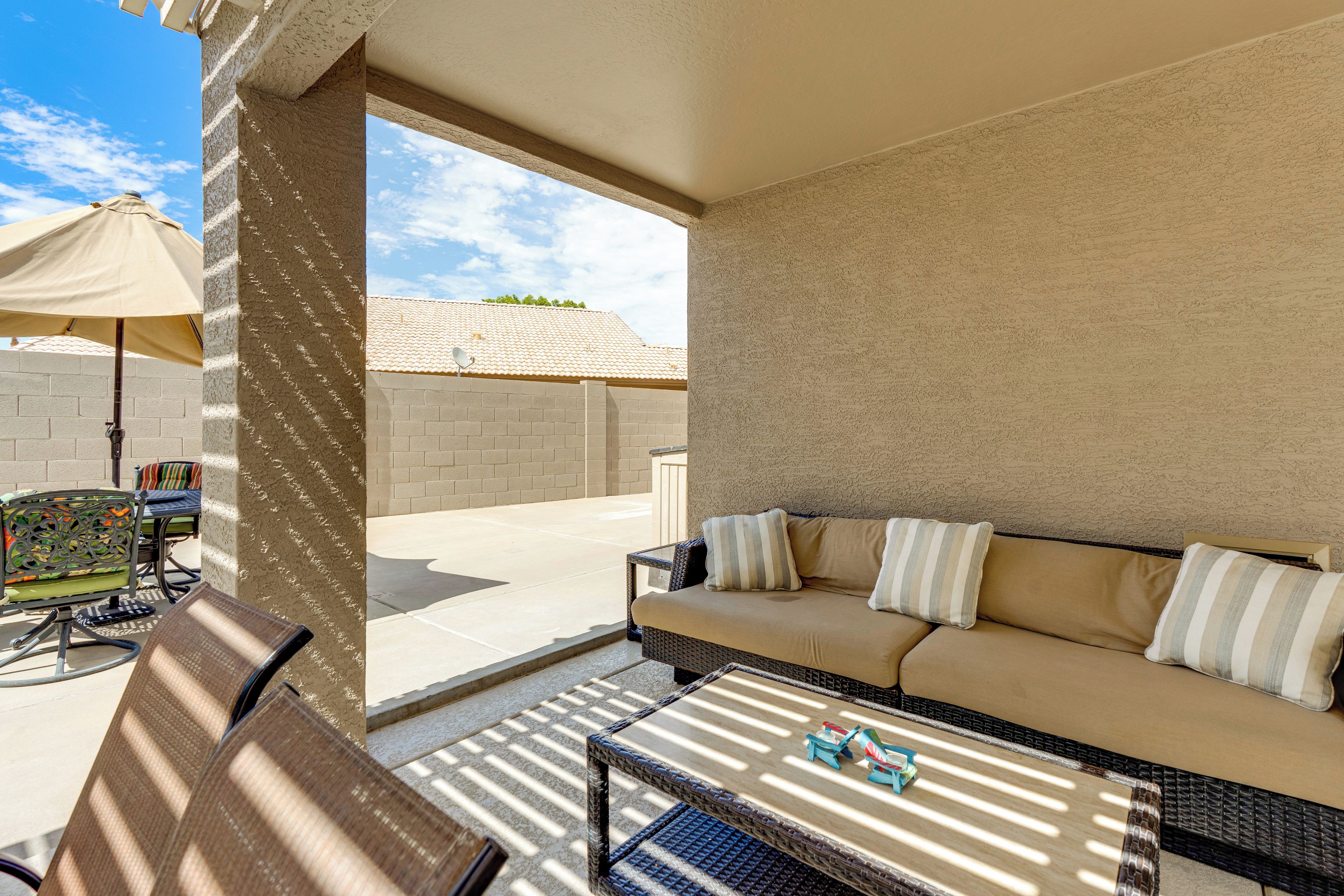 An outdoor patio area with a sofa, chairs, and a table.