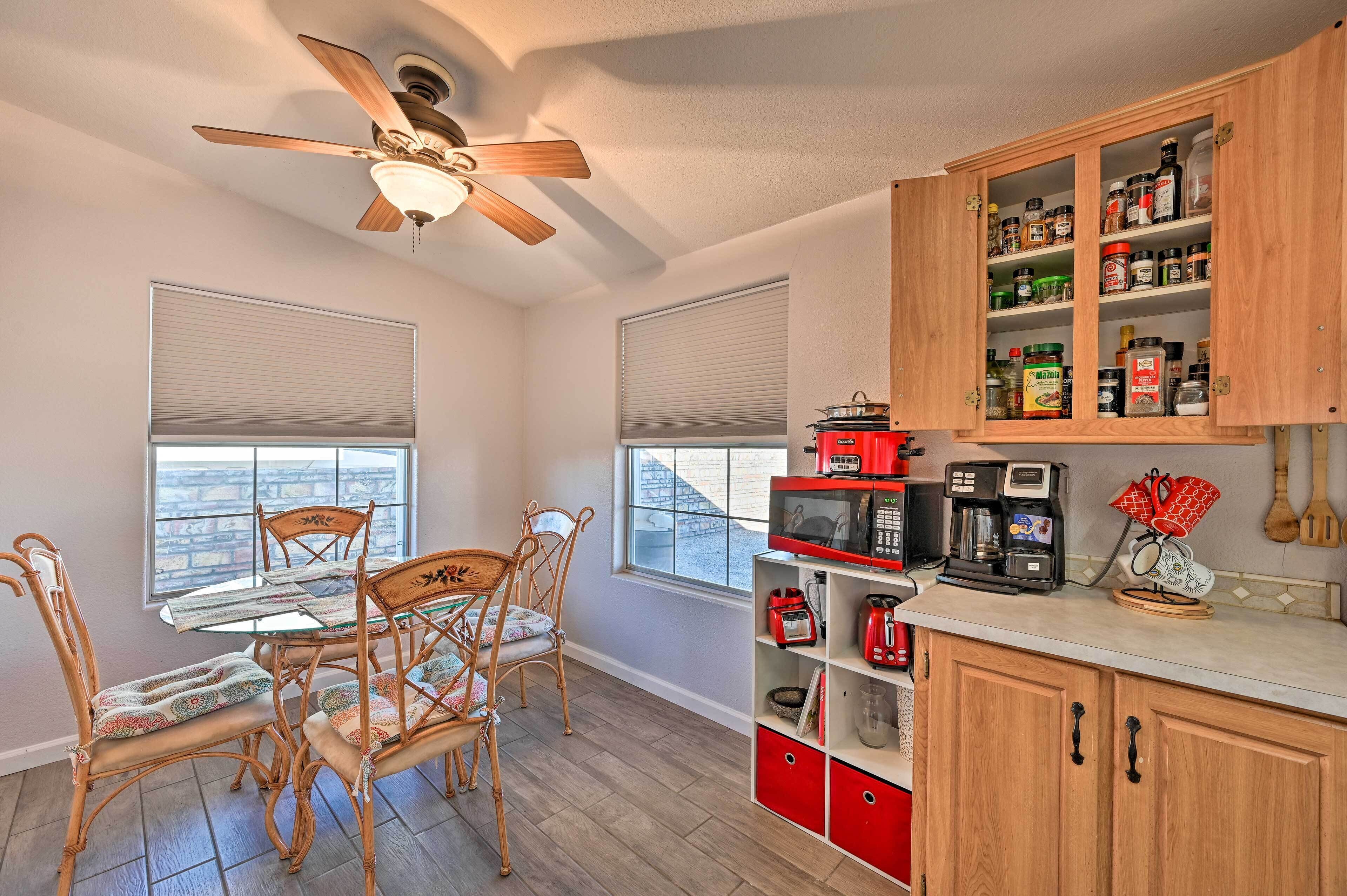 Une cuisine équipée d’une table à manger, de chaises, d’un ventilateur de plafond et d’un étagère à épices.