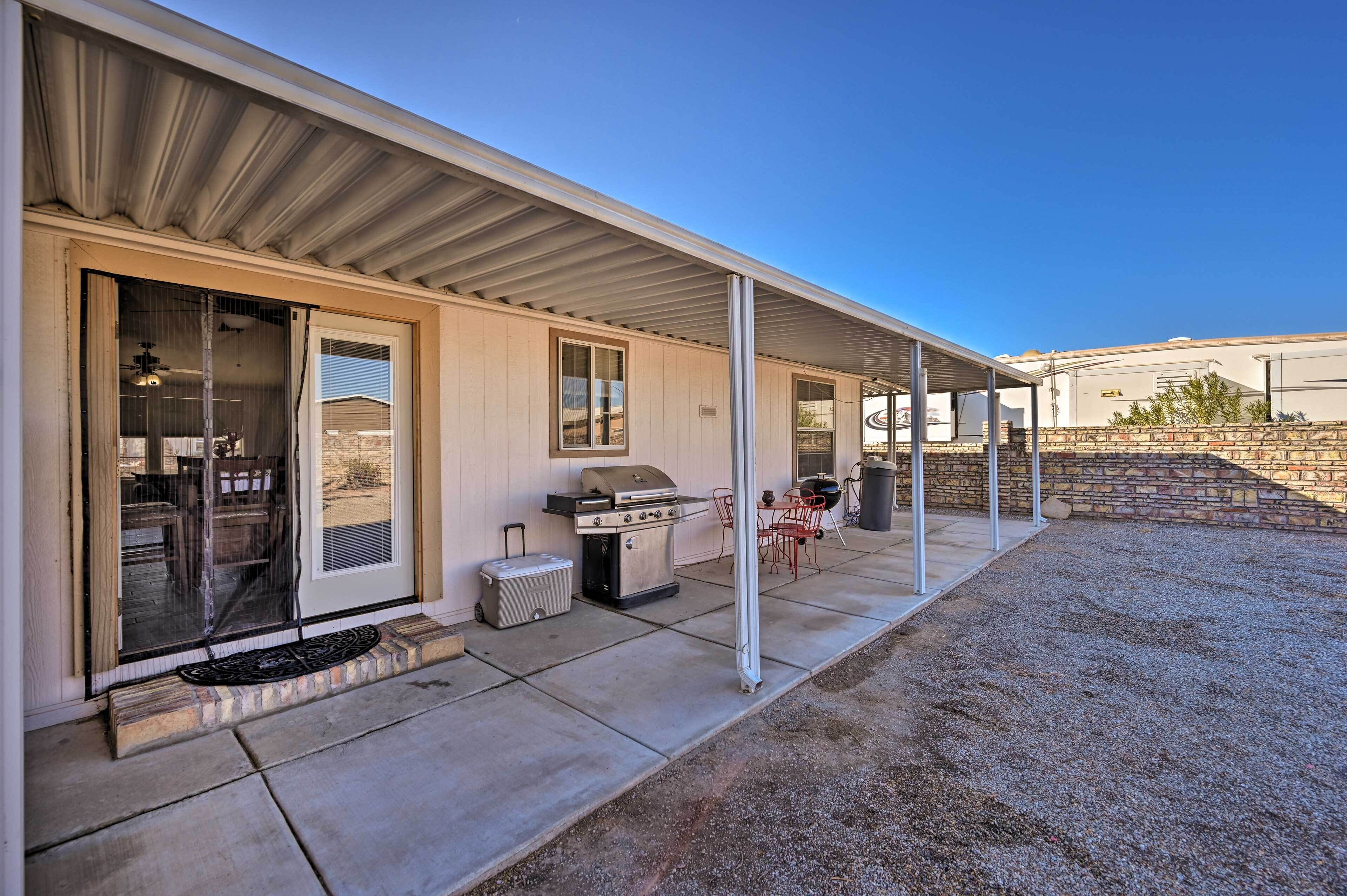 A covered patio with a grill, a sliding glass door, and a small outdoor seating area.