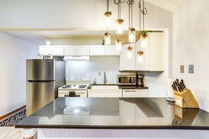 A modern kitchen with stainless steel appliances, a black granite countertop, and pendant lighting. - Cozy Norfork Home by White River: Hike + Fish (Norfork)