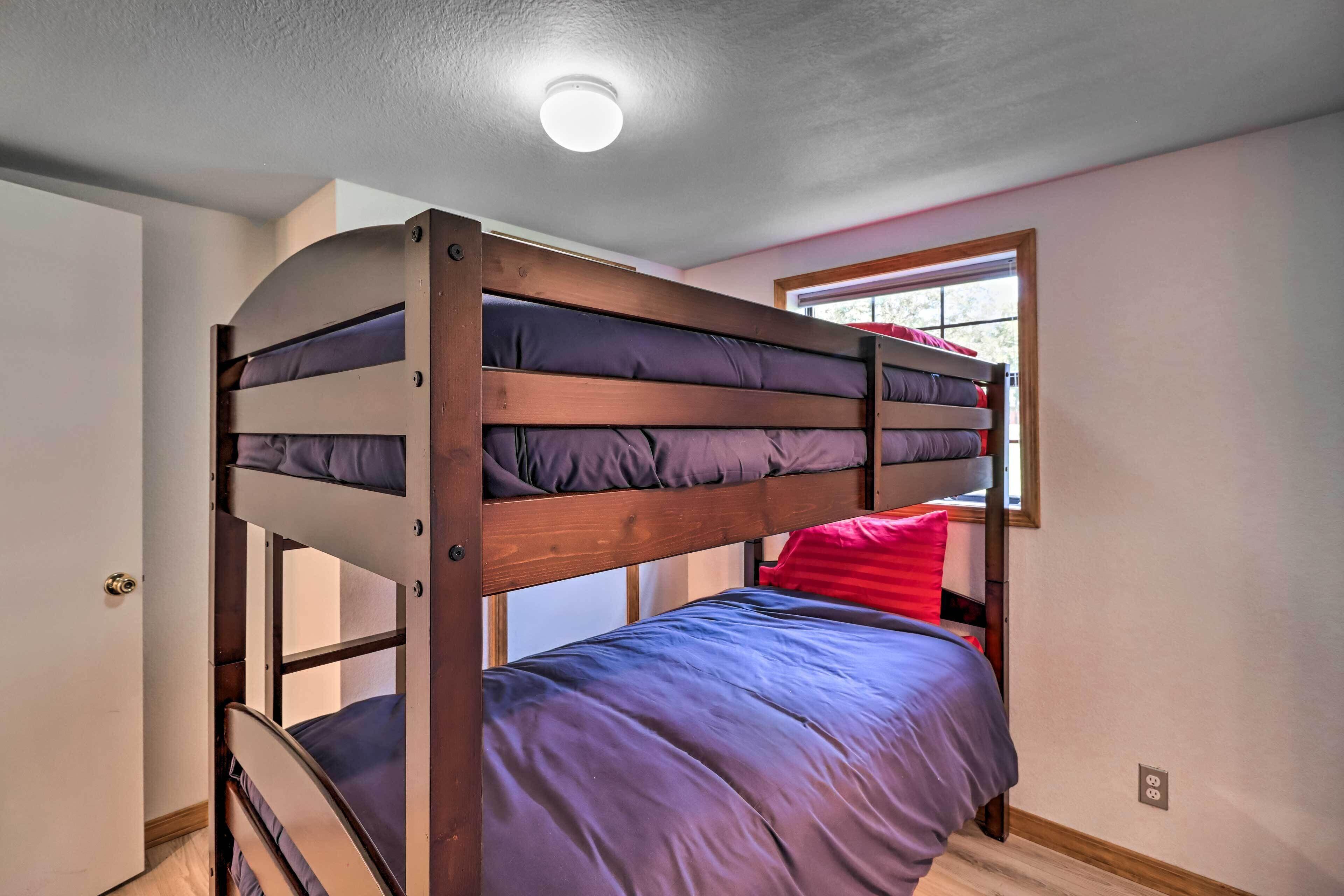A bunk bed with a window above it, a door to the left, and a light fixture on the ceiling.