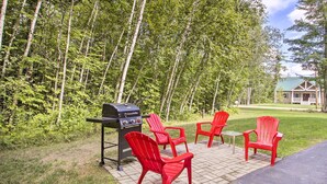 A patio with red Adirondack chairs, a grill, and a small table. - Readfield Retreat w/ Lake Maranacook Views! (Readfield)