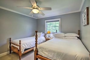 A bedroom with two wooden beds, a ceiling fan, a window, and a bedside table with a lamp. - Readfield Retreat w/ Lake Maranacook Views! (Readfield)