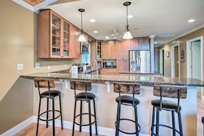 A kitchen with wooden cabinets, a granite countertop, and three bar stools. - Readfield Retreat w/ Lake Maranacook Views! (Readfield)