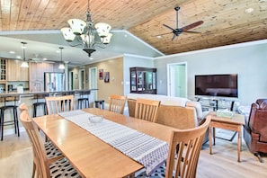 A spacious dining area with a wooden table and chairs, a chandelier, and a ceiling fan. - Readfield Retreat w/ Lake Maranacook Views! (Readfield)