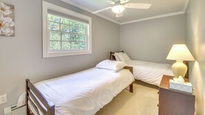 A bedroom with two single beds, a ceiling fan, a window with a view of trees, and a bedside table with a lamp and tissues. - Readfield Retreat w/ Lake Maranacook Views! (Readfield)