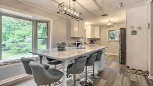 A modern kitchen with a large island, bar stools, and a view of the outdoors. - Updated High Point Retreat w/ Pool & Backyard (High Point)
