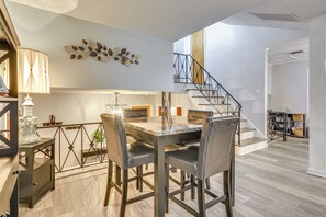 Enjoy meals in this dining area with a marble table and six chairs, surrounded by a decorative leaf wall art piece.