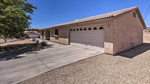 A single-story house with a garage, a concrete driveway, and a small tree to the left.