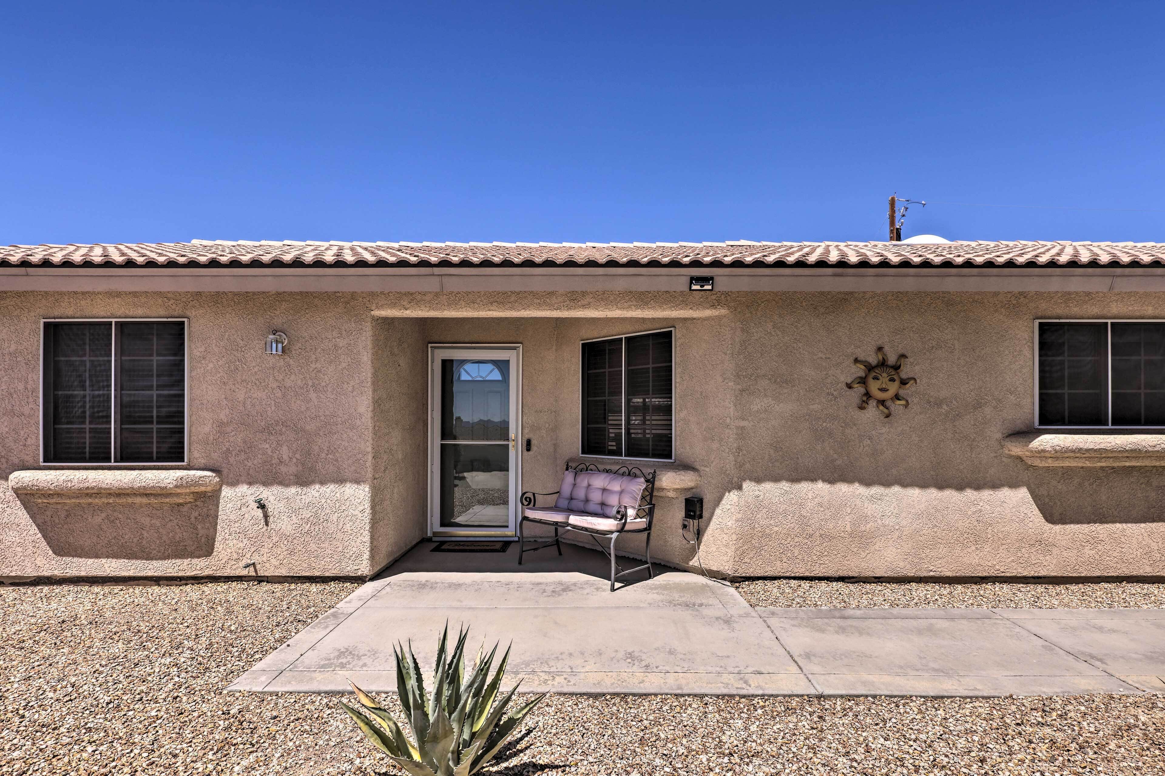 A stucco building with a tiled roof, a sliding glass door, a bench, and a small garden area.