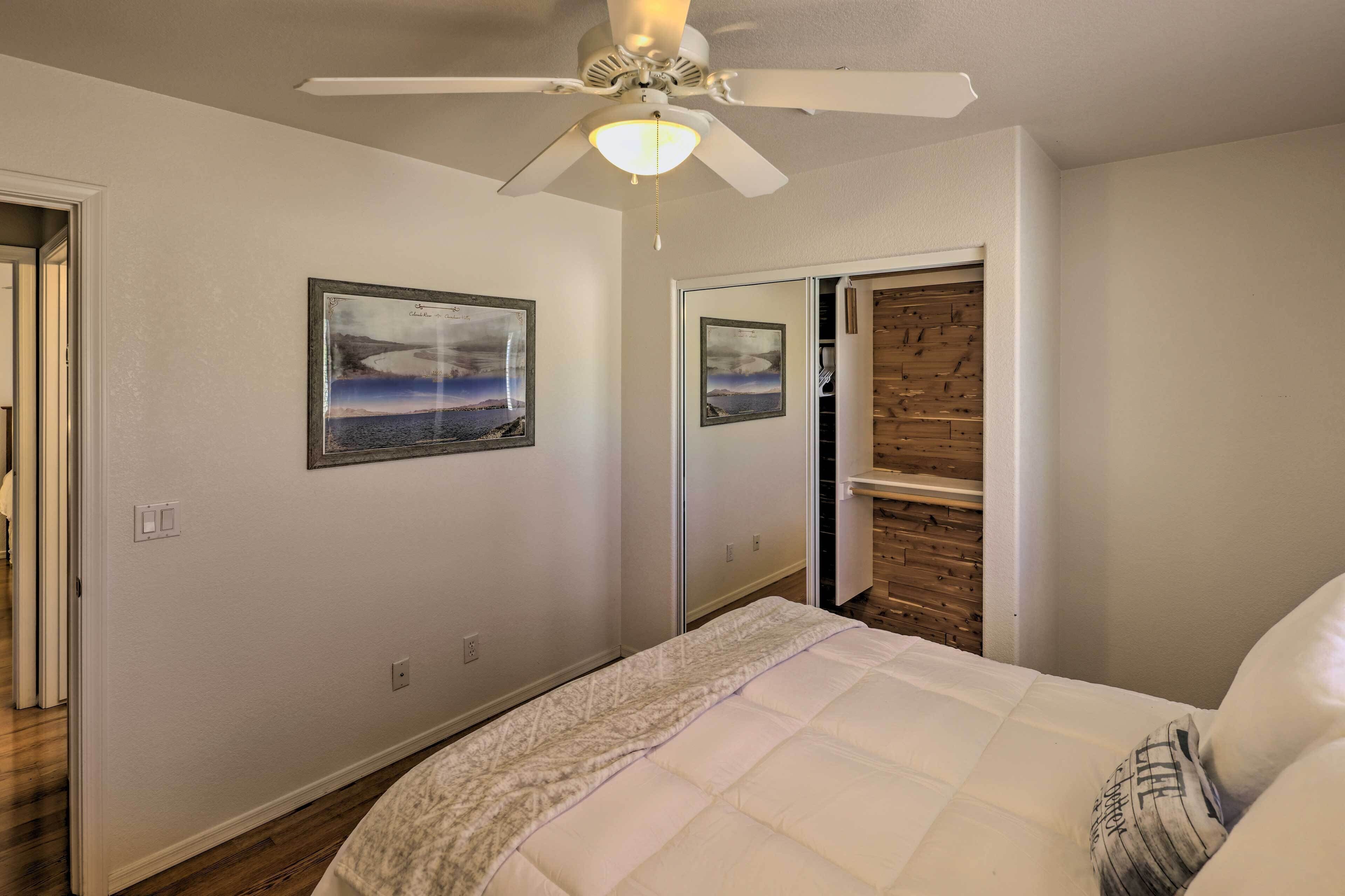 Une chambre à coucher avec un lit, un ventilateur de plafond et deux tableaux encadrés accrochés au mur.