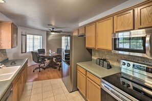 A kitchen with wooden cabinets, a stainless steel refrigerator, a microwave, and an oven. - Lake Havasu City Home w/ Patio ~ 3 Mi to Lake (Lake Havasu City)