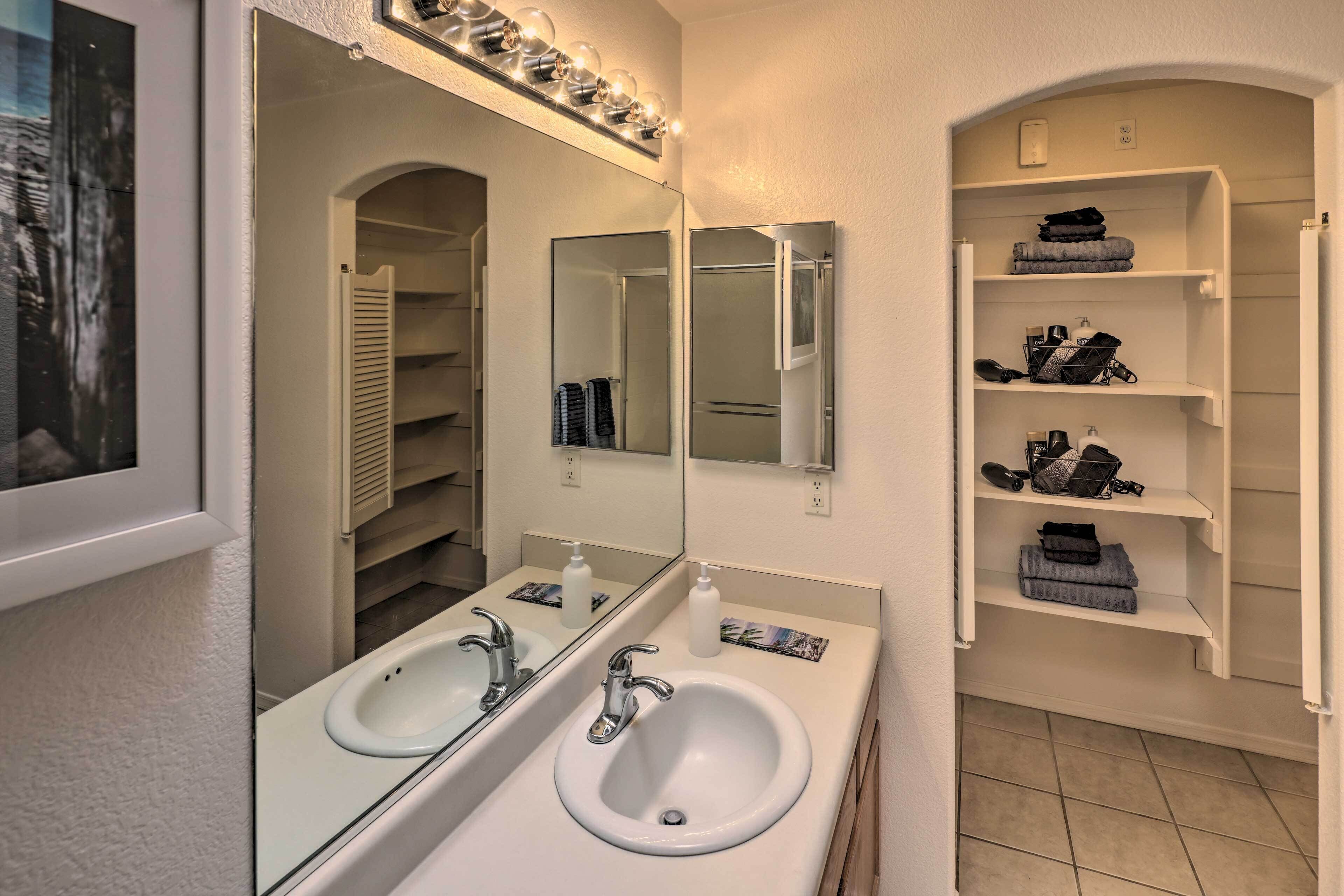 A bathroom with two sinks, a large mirror, and a vanity with shelves.