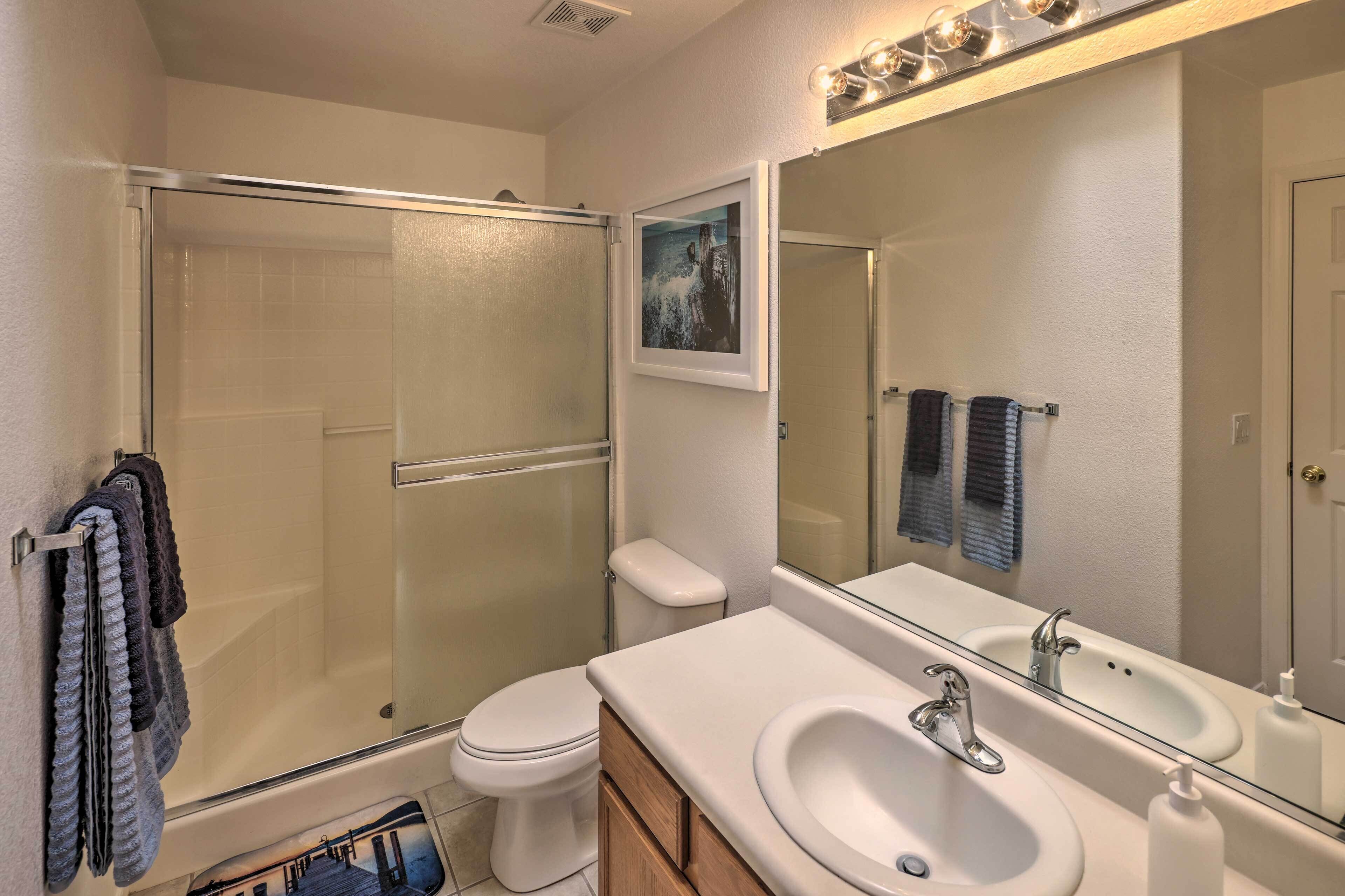 A bathroom with a glass-enclosed shower, a white sink, and a large mirror.