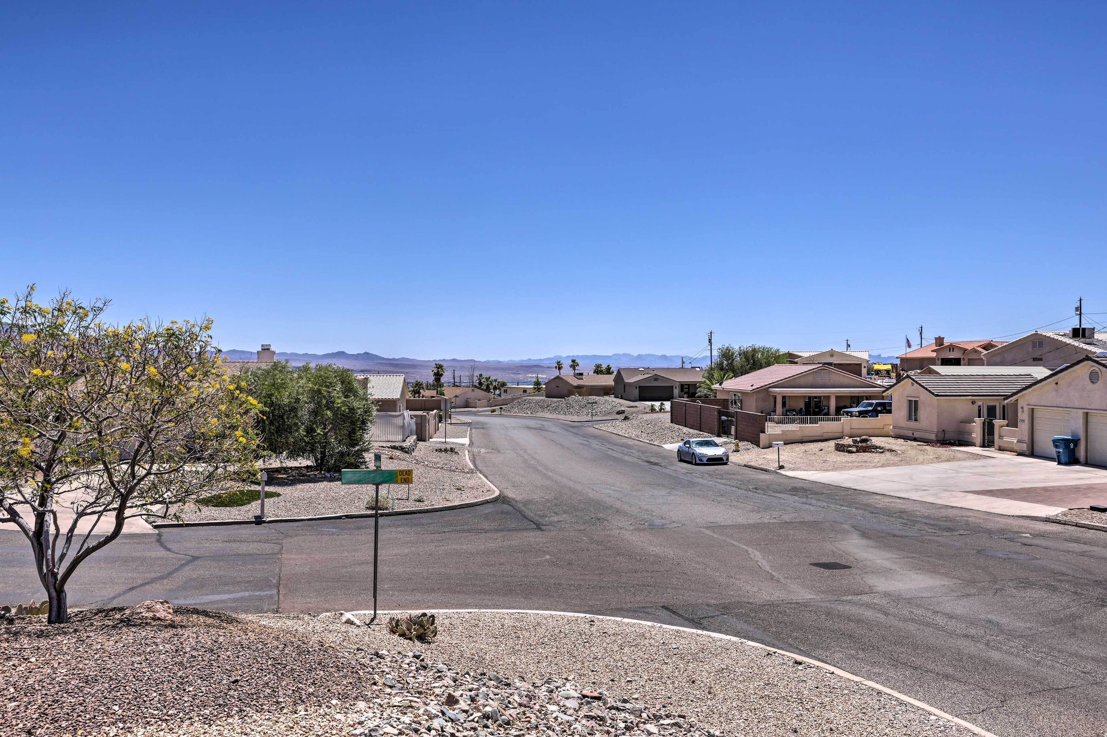 A residential street with houses, a clear sky, and a distant mountain range.