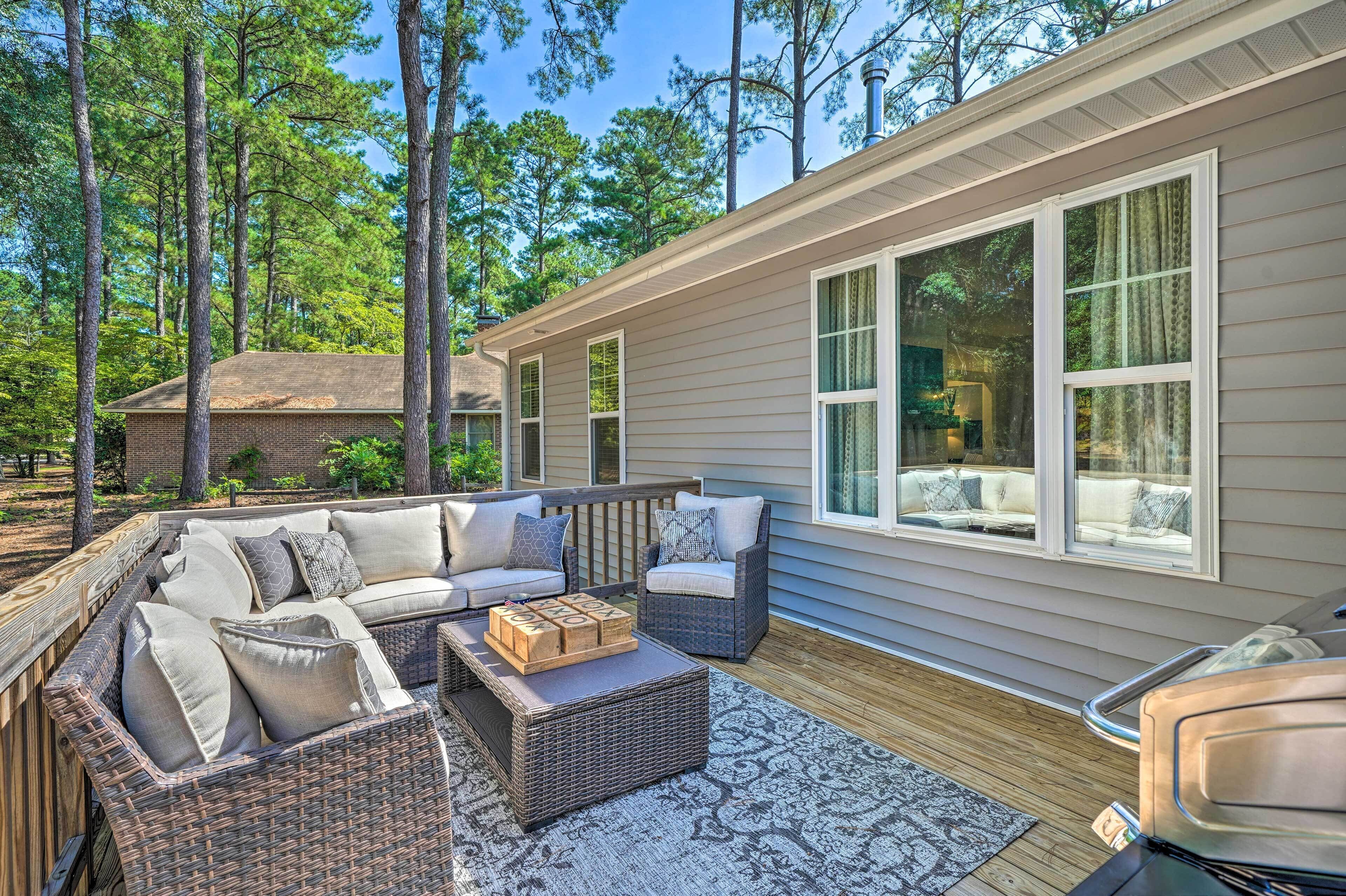 A covered outdoor deck with wicker furniture and a fireplace.