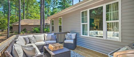 A covered outdoor deck with wicker furniture and a fireplace.
