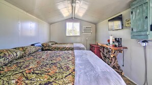 Un motel pequeño con una habitación individual, dos camas, un kitchenette, un ventilador de techo y una ventana.