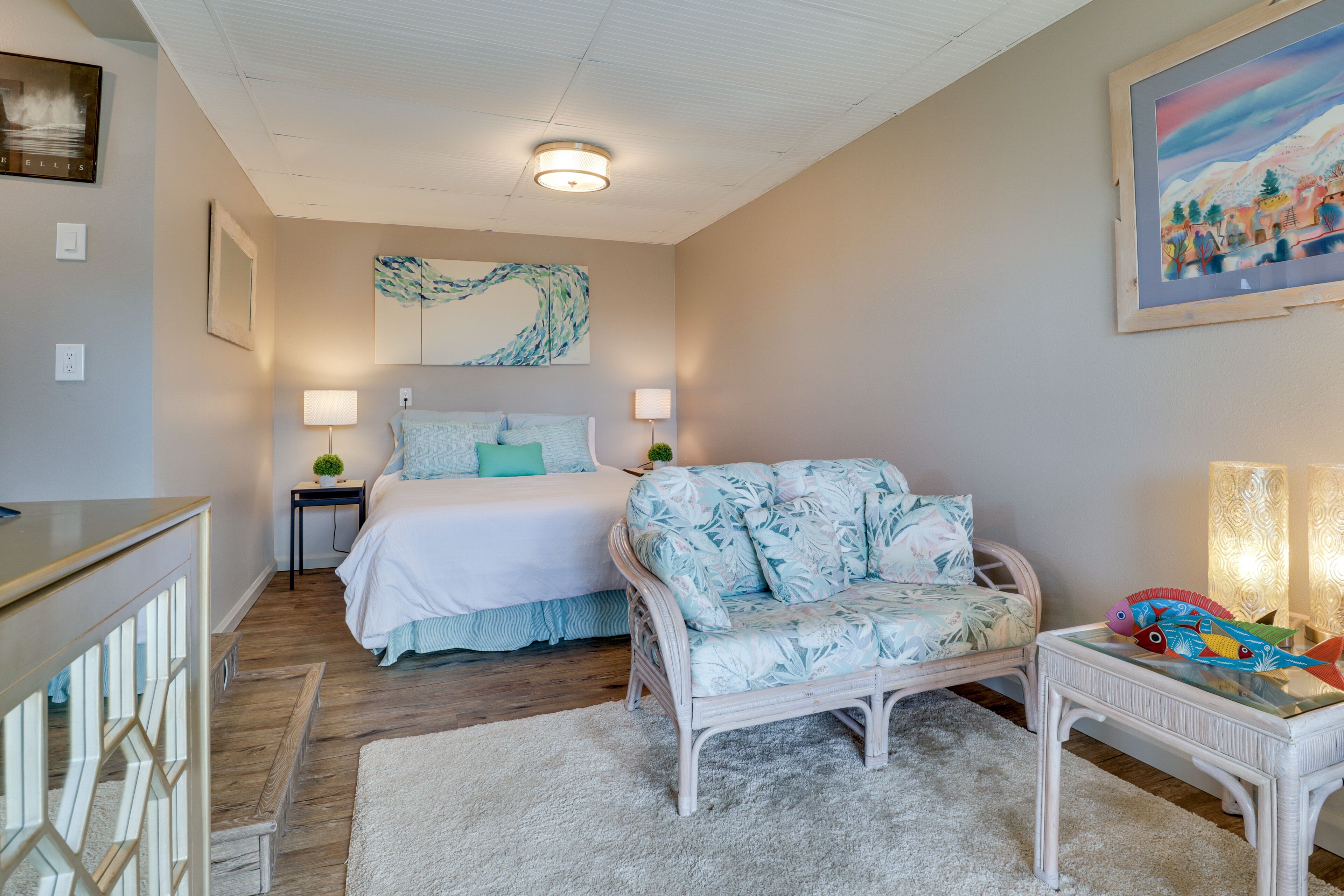 A bedroom with a bed, bedside tables, a chair, a small table, and a painting on the wall.