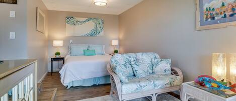 A bedroom with a bed, bedside tables, a chair, a small table, and a painting on the wall.