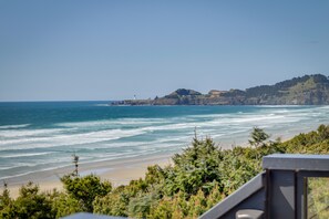 A coastal landscape with a beach, ocean waves, and a hill with a lighthouse. - Pacific Penthouse With Sunroom & Ocean Views! (Newport)