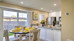 A modern kitchen with white cabinets, a stainless steel refrigerator, and a dining area with a table set for four. - Arizona Condo w/ Community Pool & Hot Tub (Mesa)