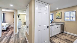 A hotel room with a wooden floor, a bed with a patterned bedspread, a kitchenette with a sink and cabinets, and a bathroom with a shower and toilet. - Arizona Condo w/ Community Pool & Hot Tub (Mesa)