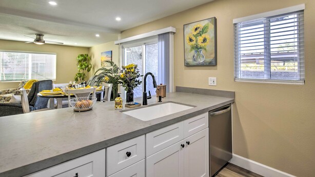 A kitchen with a large island, white cabinets, a sink, and a window with blinds. - Arizona Condo w/ Community Pool & Hot Tub (Mesa)