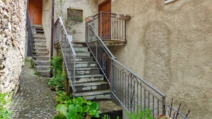 Una stretta scala in pietra con ringhiere in metallo che conduce a una porta in legno.