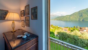 A room with a view of a lake and mountains, a lamp, and framed pictures on the wall. - Ca Furmiga by Wonderful Italy (Tremezzina)