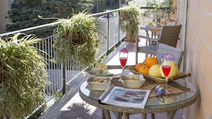 A balcony with potted plants, a wicker table with fruits, a glass of red drink, and a newspaper. - Casa Rosangela in Sorrento (Sorrento)
