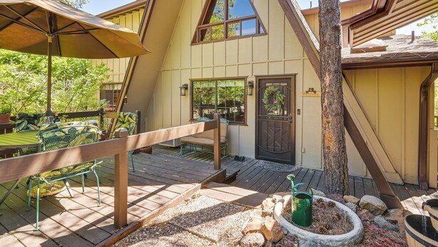 A wooden deck with outdoor seating, a welcome sign, and a door with a wreath.