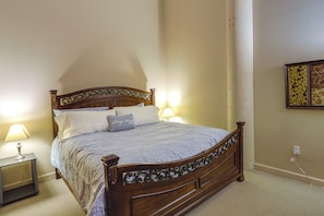 A neatly made bed with a wooden headboard, two bedside lamps, and a wall-mounted artwork. - Waterfront Sandusky Vacation Rental: Downtown! (Sandusky)