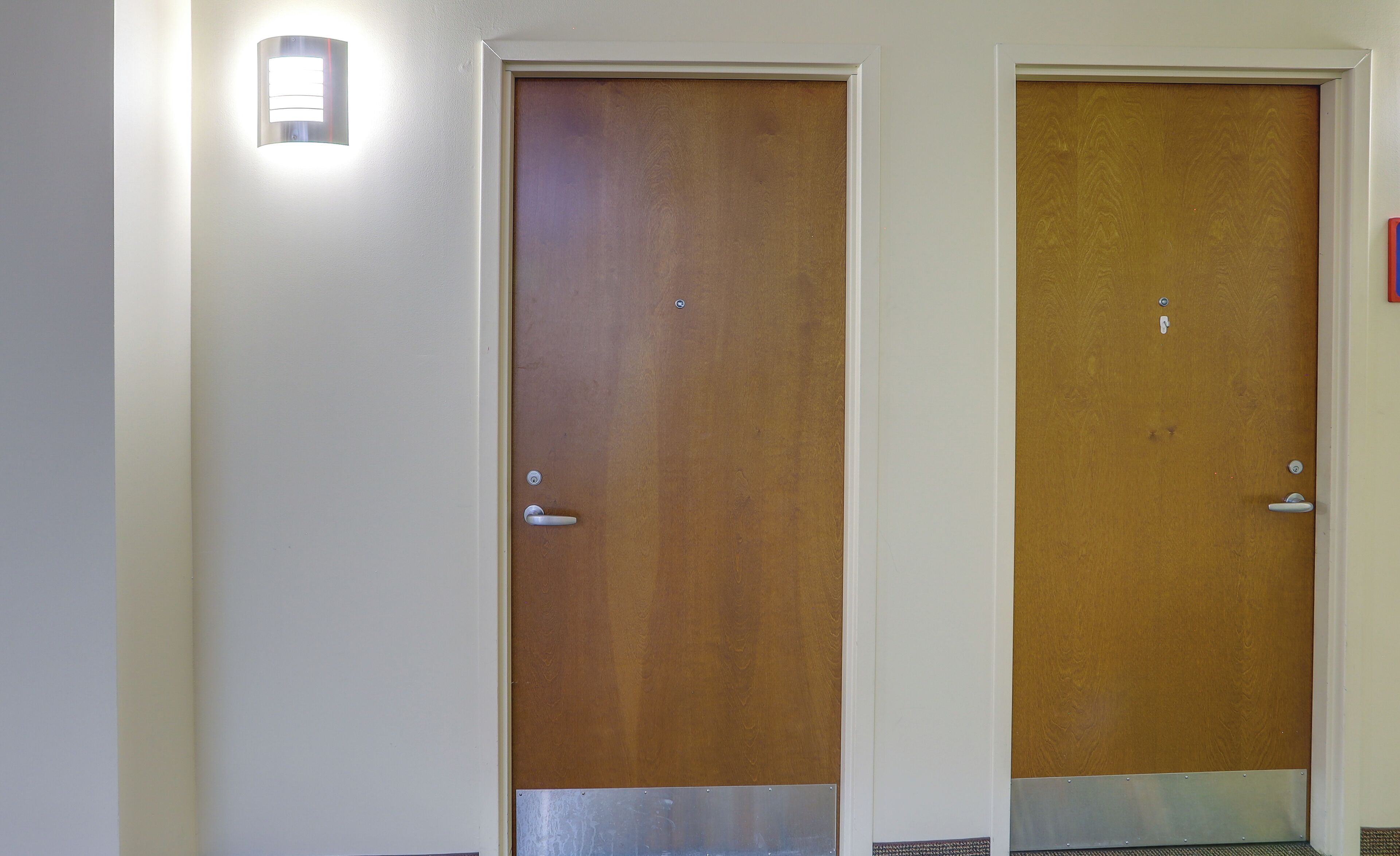 Two wooden doors with metal handles and a light fixture above the left door.