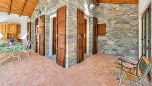Um quarto com paredes de pedra, portas de madeira, chão de azulejos e um banco.