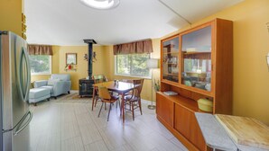 A compact kitchen with a dining area, a refrigerator, a sofa, and a cabinet with glass doors. - Pet-friendly Getaway w/ Porch in Banner Elk! (Banner Elk)