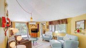 A living room with a sofa, armchair, and a glass coffee table. There is a television and a red telephone on the left. - Pet-friendly Getaway w/ Porch in Banner Elk! (Banner Elk)