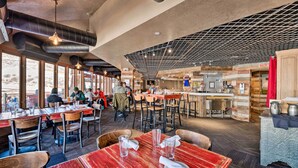 A restaurant with wooden tables and chairs, a bar area, and large windows allowing natural light. - Park City Condo: Steps to Canyons Village & Skiing (Park City)
