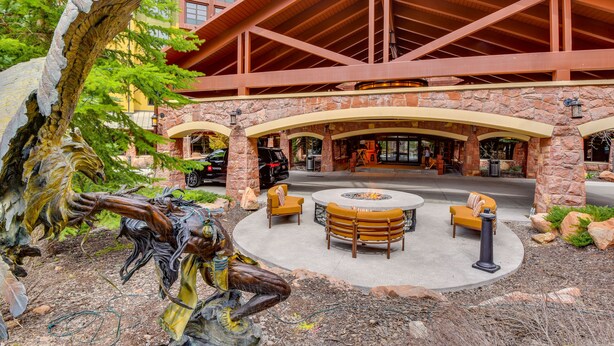 A building with a stone facade, wooden beams, and a fire pit area with seating. - Park City Condo: Steps to Canyons Village & Skiing (Park City)
