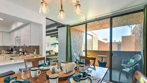 A modern kitchen with white cabinets, a dining area with a wooden table set for four, and a view of the outdoors through large sliding glass doors. - 3 Mi to Old Town: Scottsdale Condo w/ Pool & Lake (Paradise Valley)