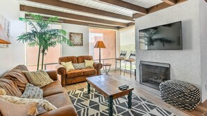 A living room with a brown leather sofa, a wooden coffee table, a patterned rug, a large plant, and a fireplace. - 3 Mi to Old Town: Scottsdale Condo w/ Pool & Lake (Paradise Valley)
