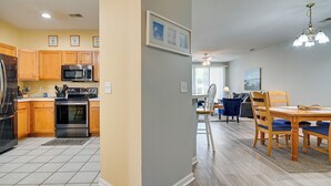Una cocina moderna con armarios de madera, electrodomésticos de acero inoxidable y un comedor con mesa de madera y sillas azules.