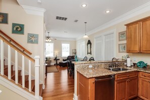A spacious kitchen with wooden cabinets, granite countertops, and a built-in dishwasher. - Waterside Village Cottage 3220 (Port St. Joe)