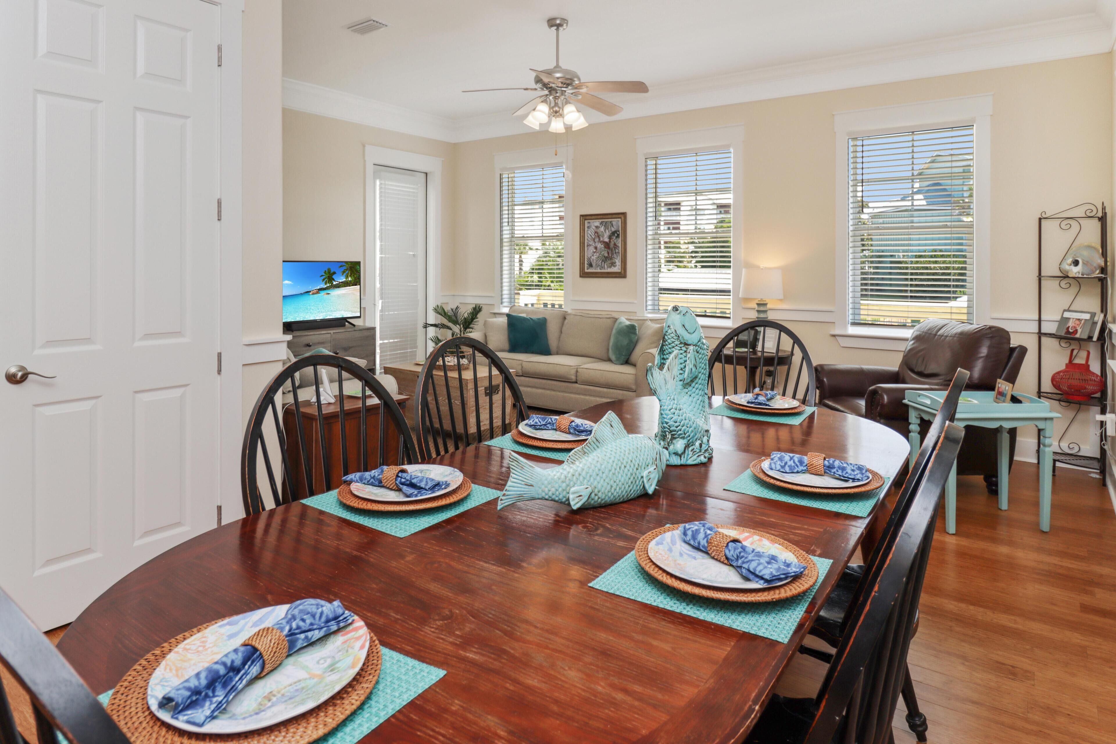 A dining room with a wooden table set for six, surrounded by chairs.
