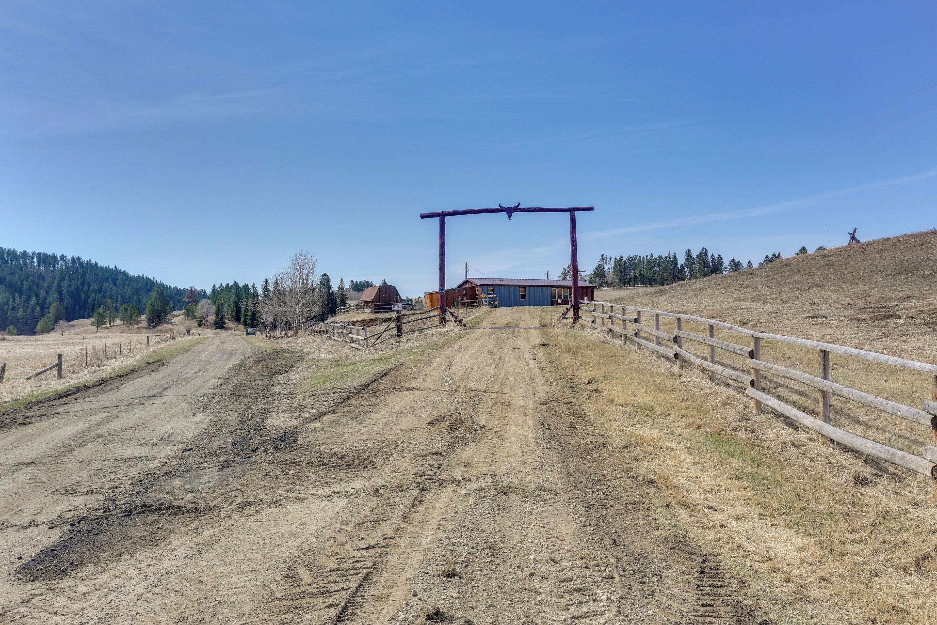 Un chemin de terre mène à une construction en bois surmontée d’une arche rouge.