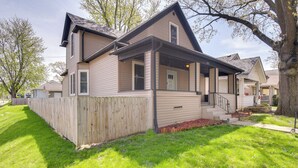 A two-story house with a front porch, a wooden fence, and a well-maintained lawn. - Pet-friendly Davenport Home - Near Casino & Golf (Davenport)